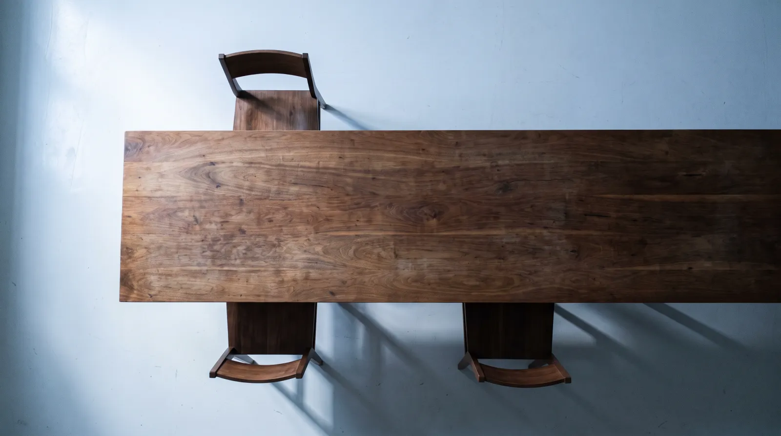 Illustrative overhead view of an empty conference table with three chairs in cool window light